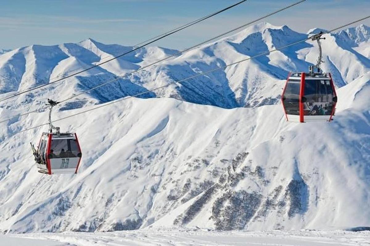 dua lift ski terbang di atas gunung yang tertutup salju