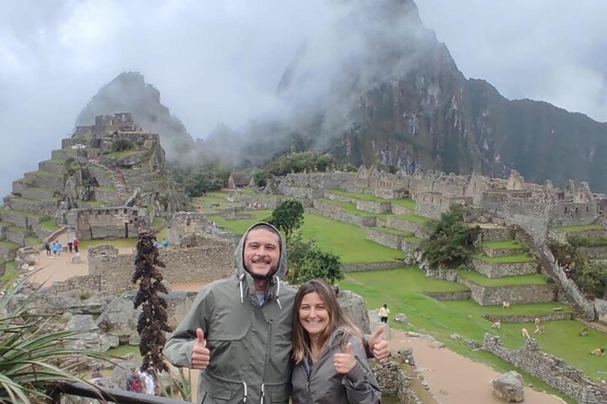 un uomo e una donna che alzano i pollici verso le rovine di una montagna