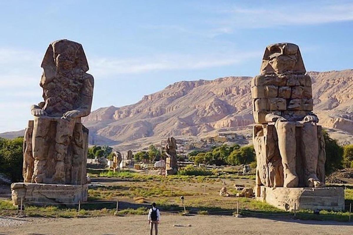 un uomo in piedi davanti a due grandi statue di pietra