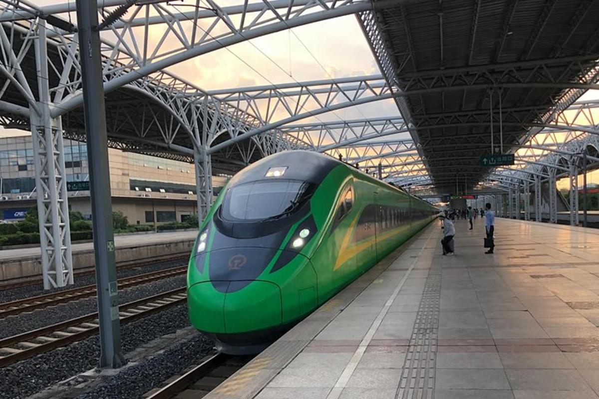 a green train is pulling into a train station