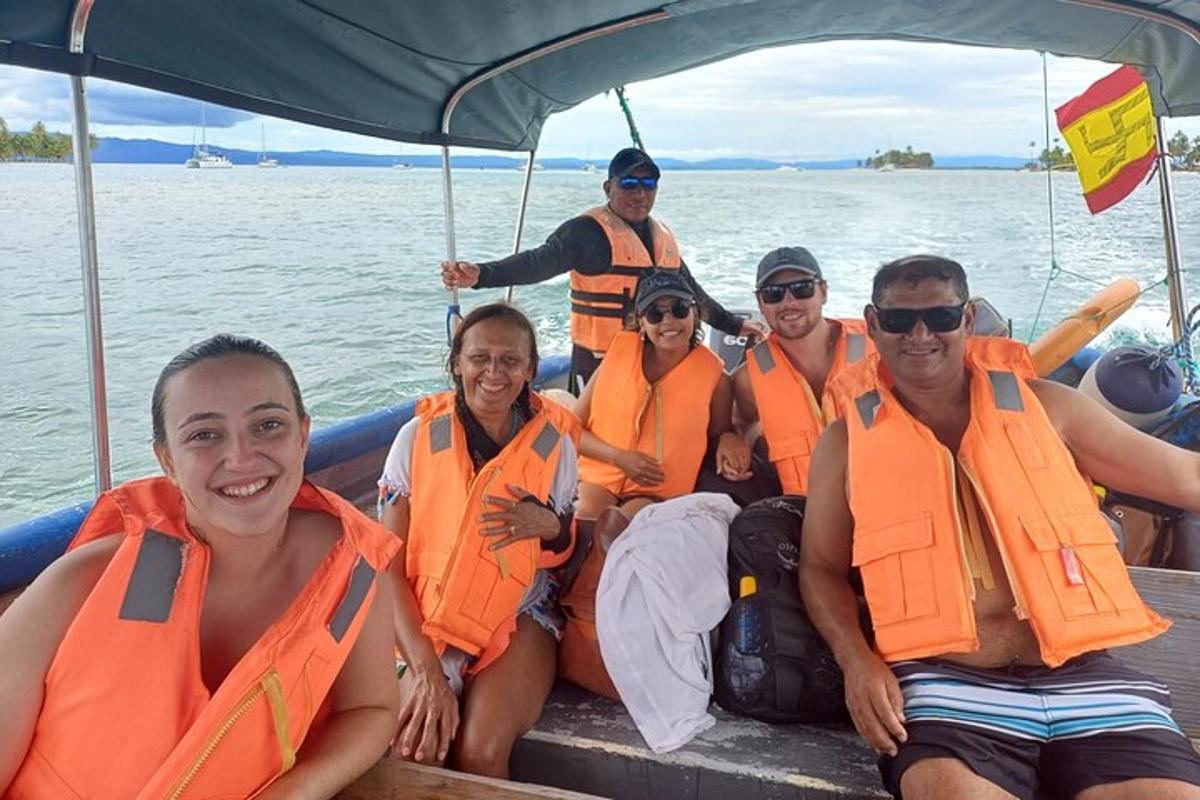 un grup de oameni în veste de salvare portocalii pe o barcă