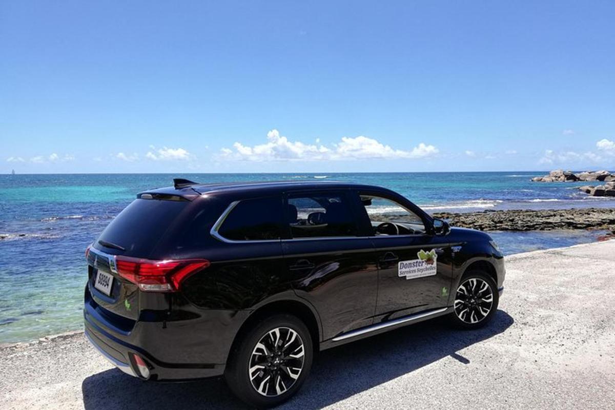 um carro preto estacionado em uma praia perto do oceano