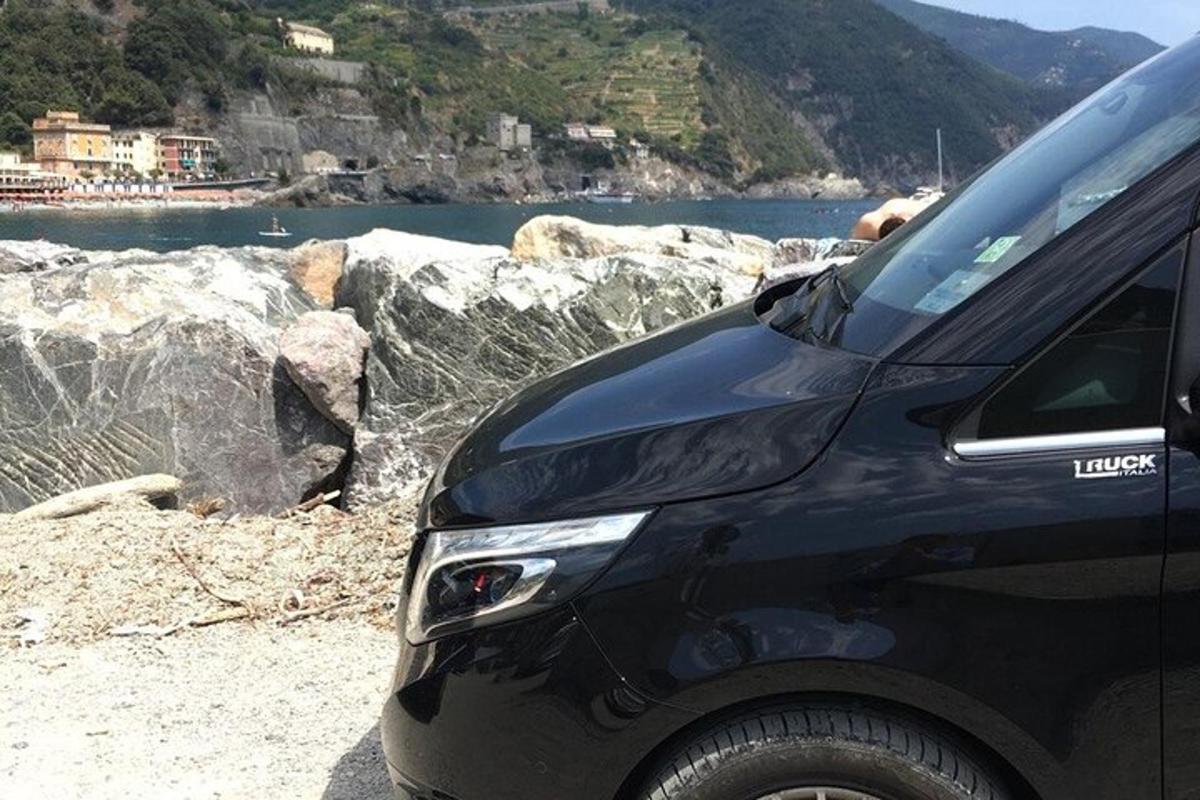 un'auto nera parcheggiata su una spiaggia vicino a uno specchio d'acqua