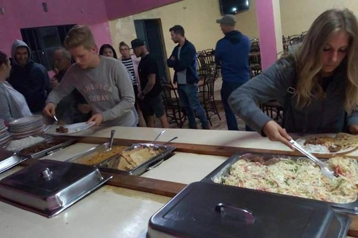 một nhóm người đứng quanh một quầy buffet với những chiếc bánh pizza