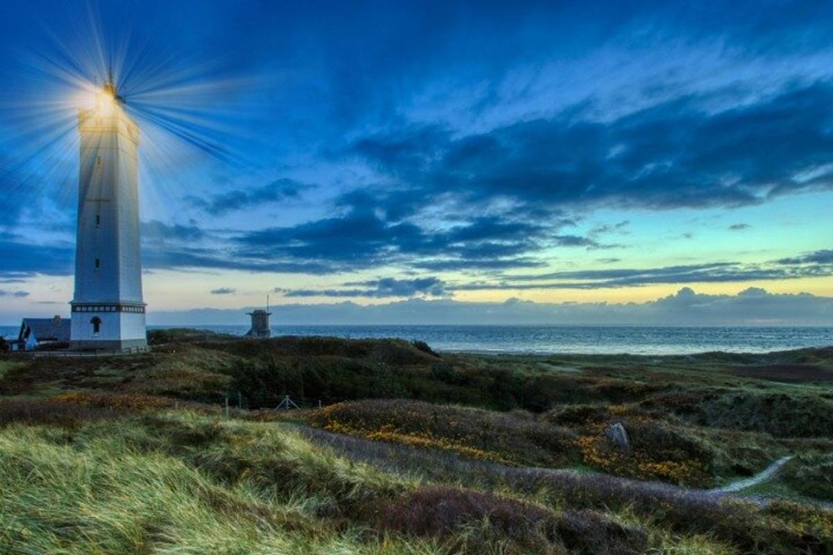 a lighthouse on a beach with the ocean in the background