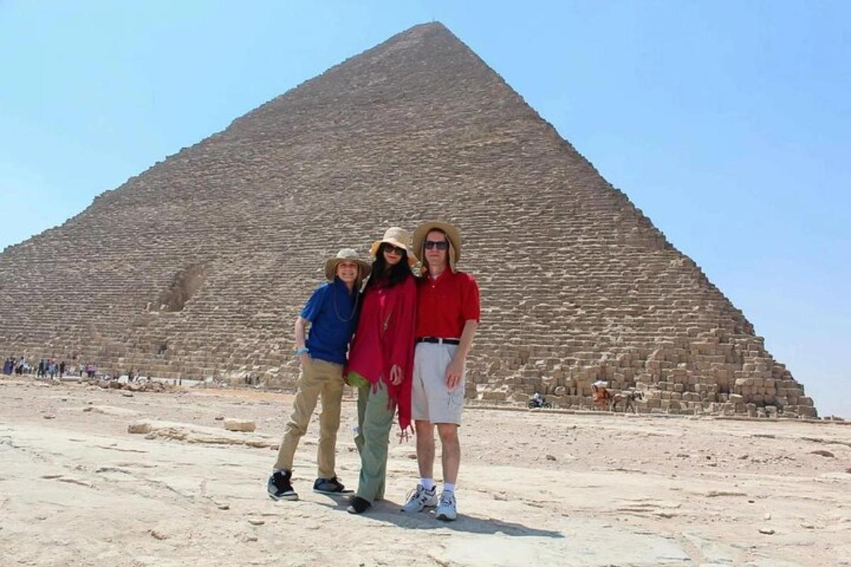 troje ljudi stoje ispred piramide