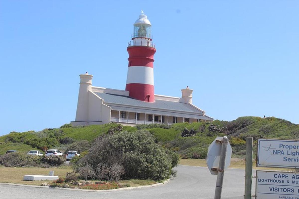a lighthouse sitting on top of a hill with a sign