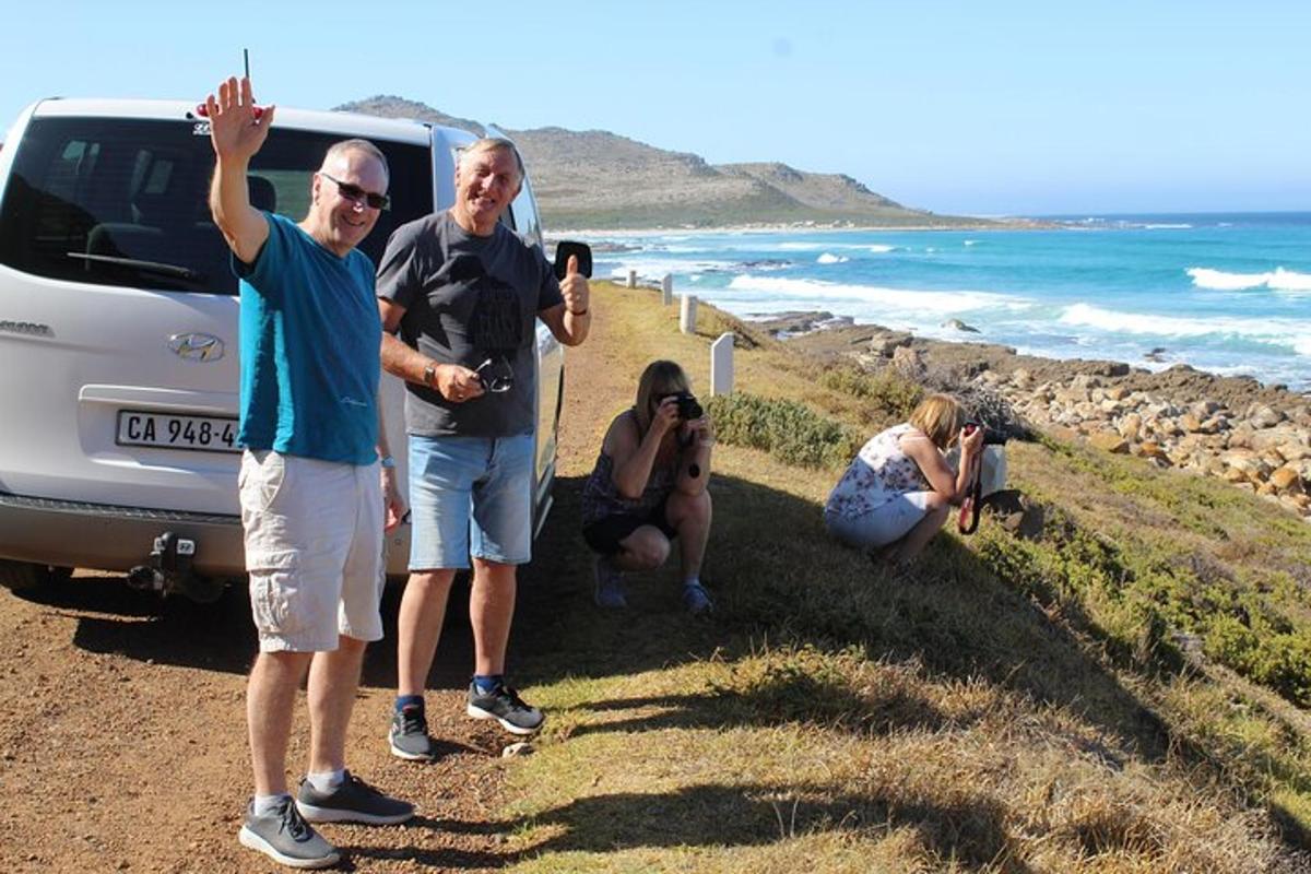 en gruppe mennesker står ved siden af en bil på en strand