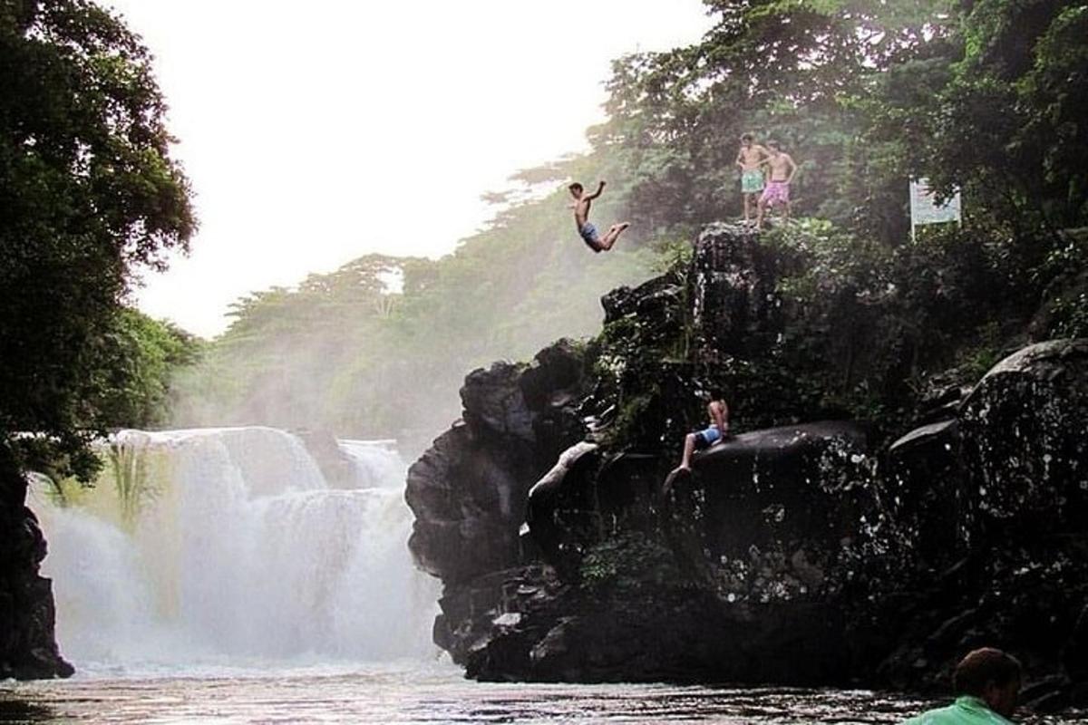 a group of people jumping off of a waterfall