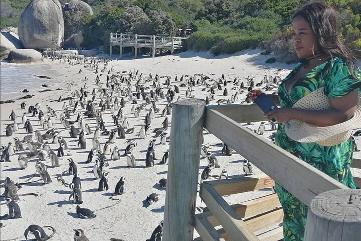 eine Frau steht neben einem Zaun mit einer Herde Pinguine