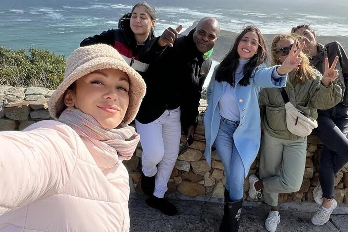 Un grupo de personas de pie en un muro cerca del océano.