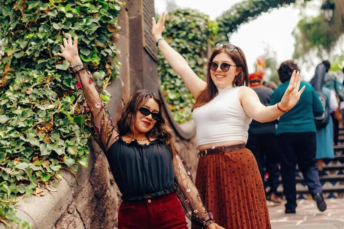two women standing next to a wall with their hands up