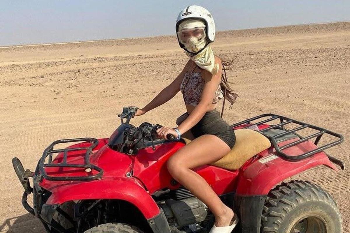 kobieta siedzi na czerwonym quadzie na pustyni