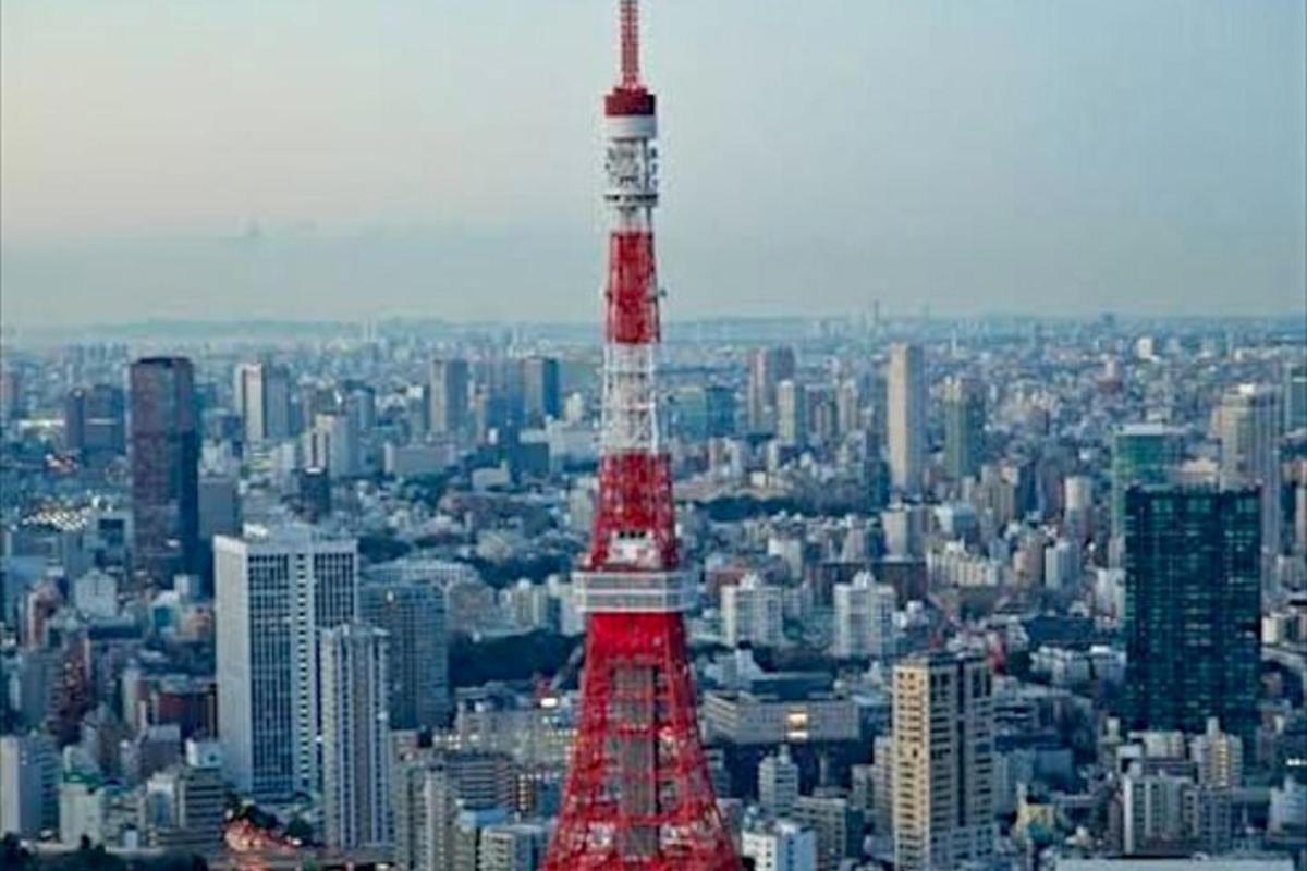 uma torre vermelha e branca em uma grande cidade