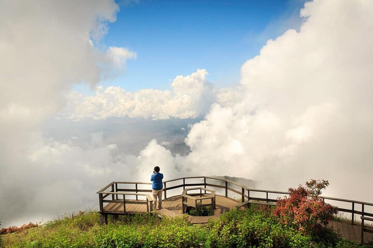 a person standing on top of a mountain with clouds