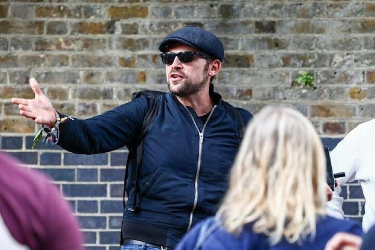 a man wearing a hat and sunglasses pointing at a woman