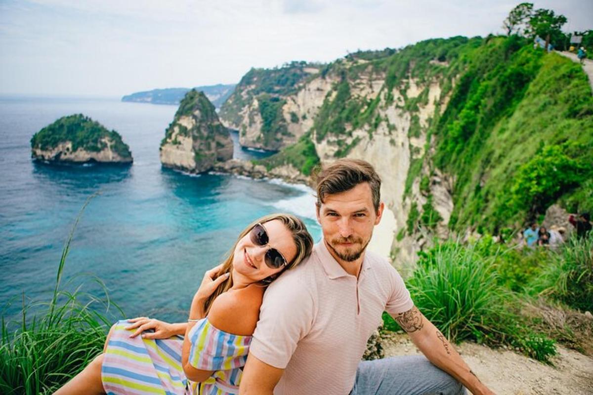 một người đàn ông và một người phụ nữ ngồi trên vách đá nhìn ra đại dương