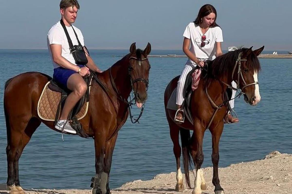 Dve ženy jazdia na koňoch na pláži