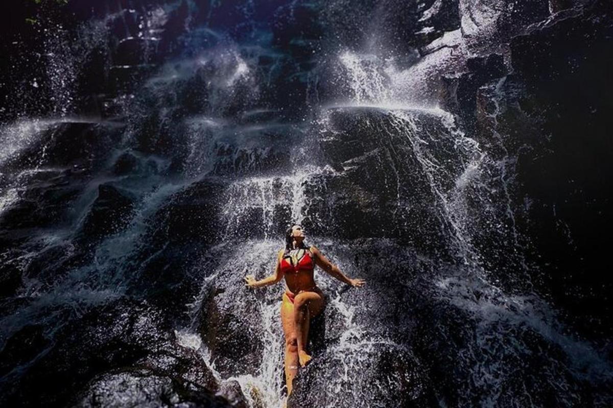 kona situr á steini fyrir framan foss