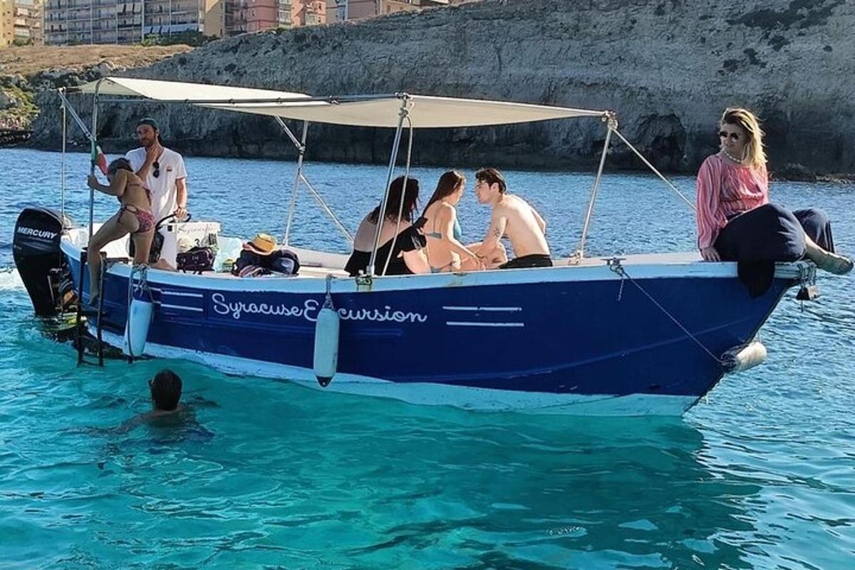 skupina ľudí sediacich na modrej lodi vo vode
