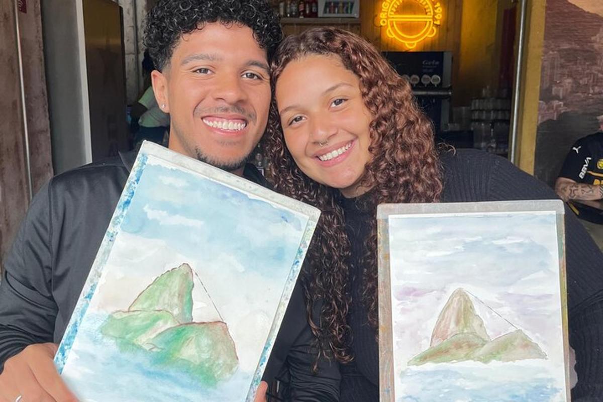 a man and a woman holding paintings of mountains