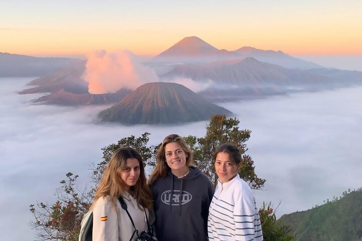 a group of three people standing in front of a mountain