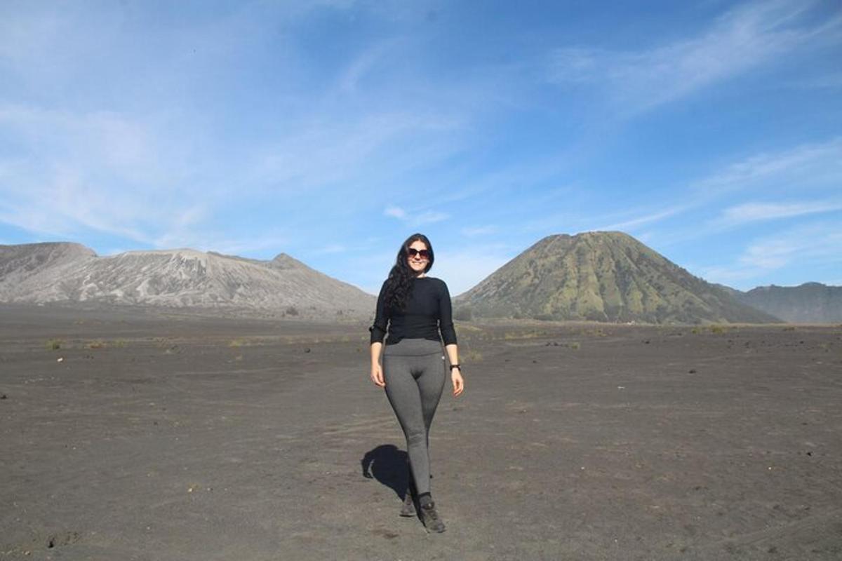 a woman standing in a field with mountains in the background