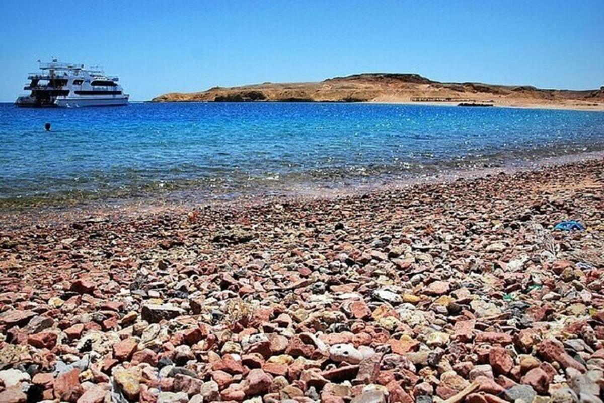 uma praia rochosa com um barco na água