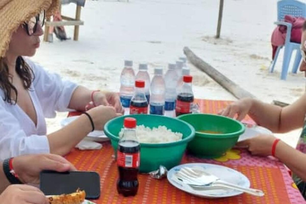 grupp inimesi istub laua taga koos toidu ja jookidega