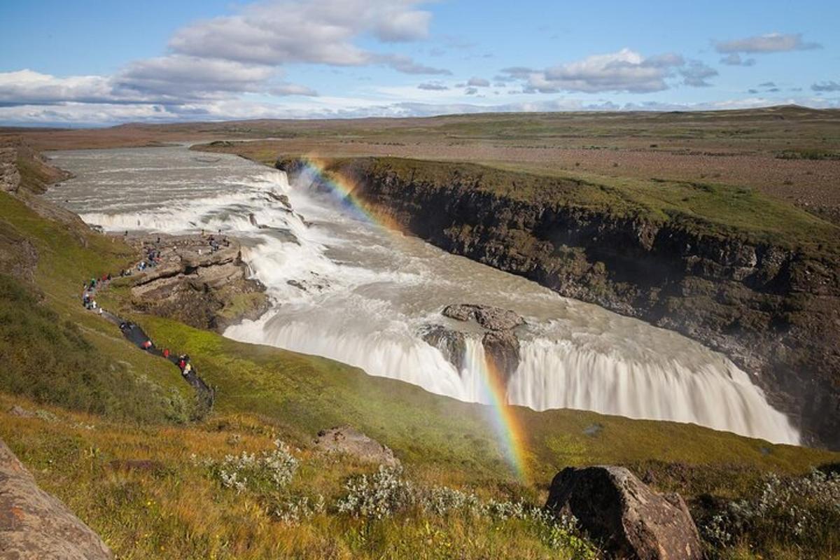 un arc-en-ciel au-dessus d'une cascade au milieu d'un champ