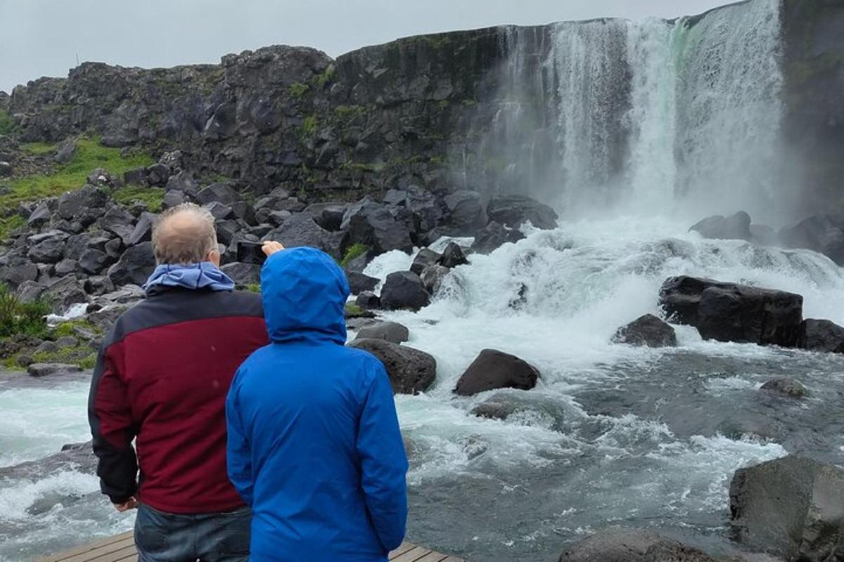 two people standing in front of a waterfall