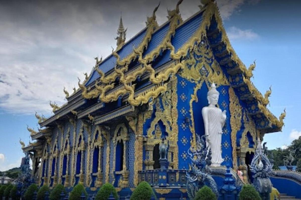 một tòa nhà màu xanh và vàng với một bức tượng ở phía trước