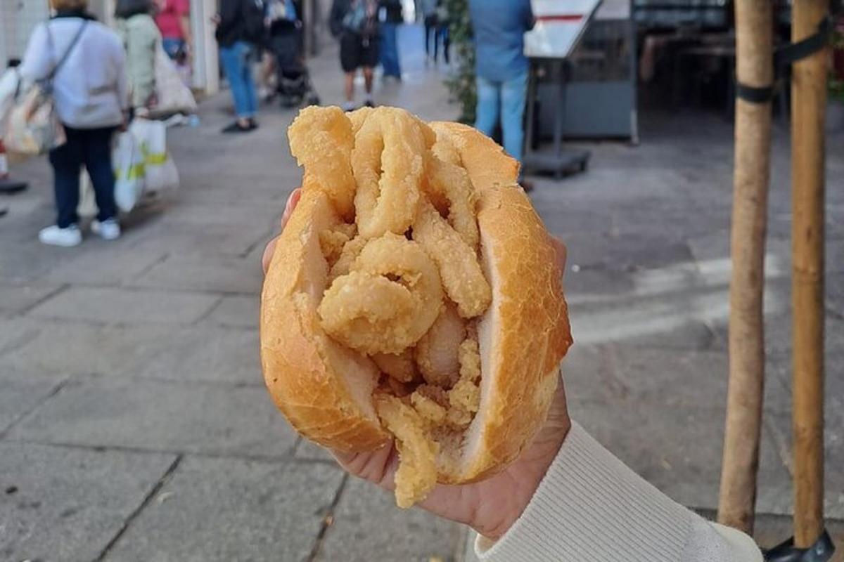 a person holding a piece of shrimp in a bun