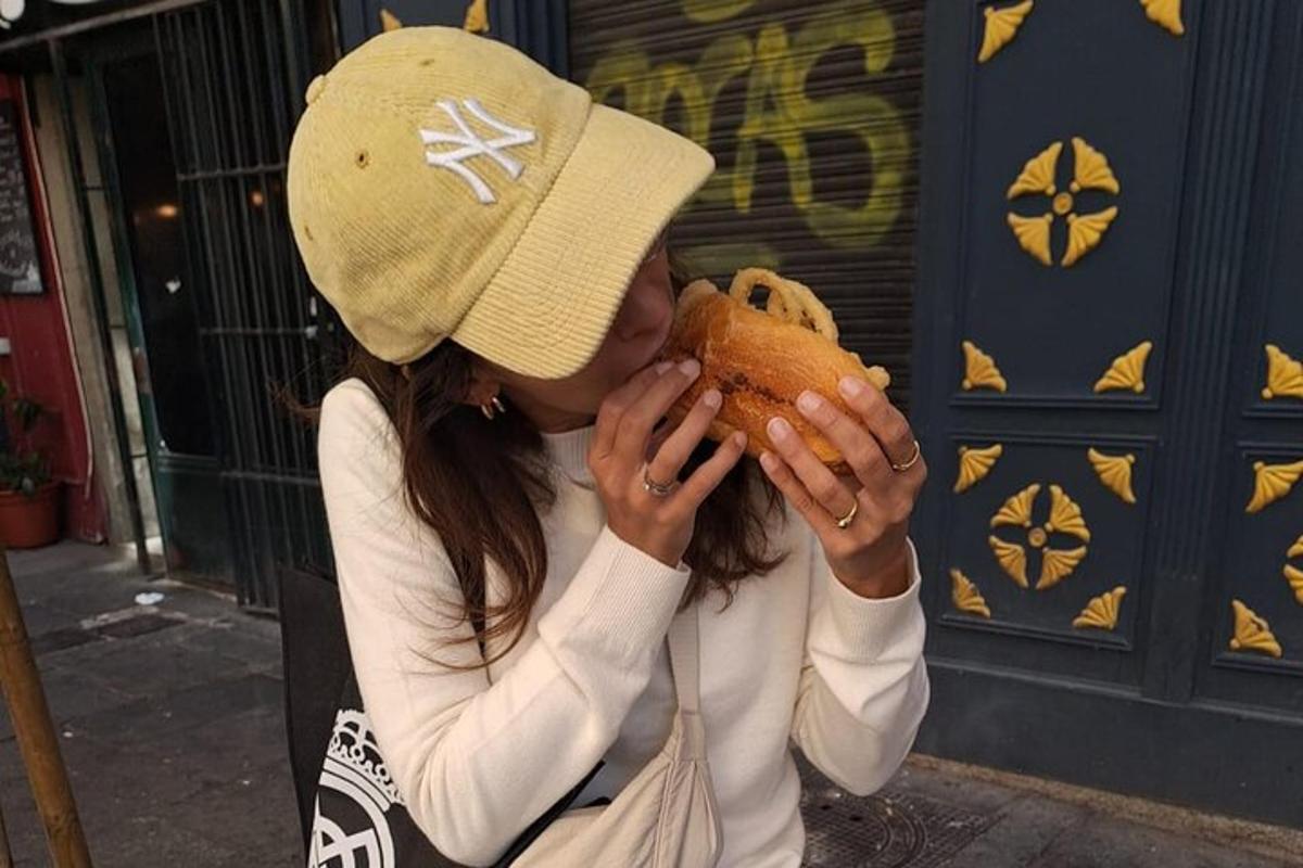 a woman wearing a hat eating a hot dog