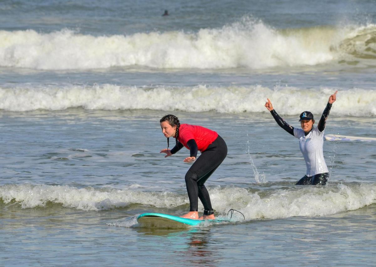 to personer som rir på en bølge på et surfebrett i havet