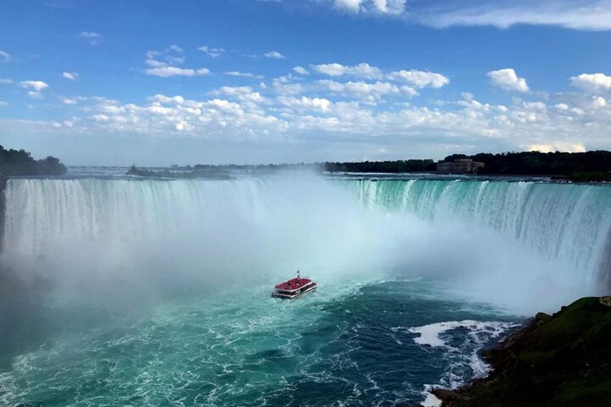 a boat in the water in front of a waterfall