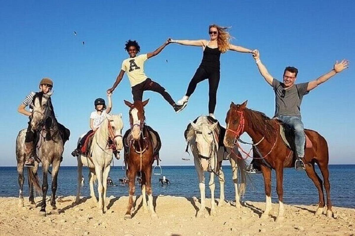 en gruppe mennesker som rir på hester på stranden