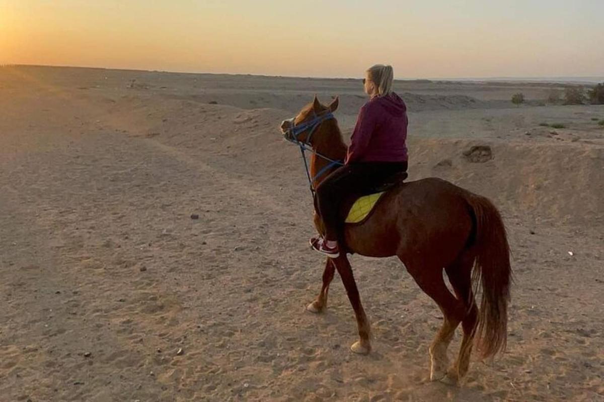 eine Frau, die in der Wüste auf einem Pferd reitet