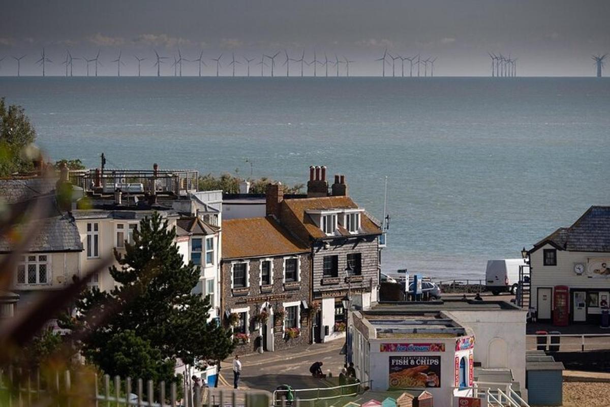 a group of buildings with wind turbines in the ocean