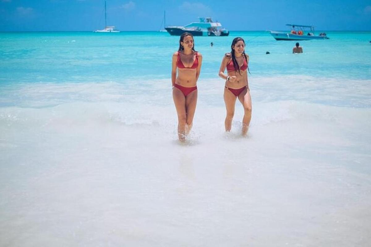 two women walking in the water on a beach