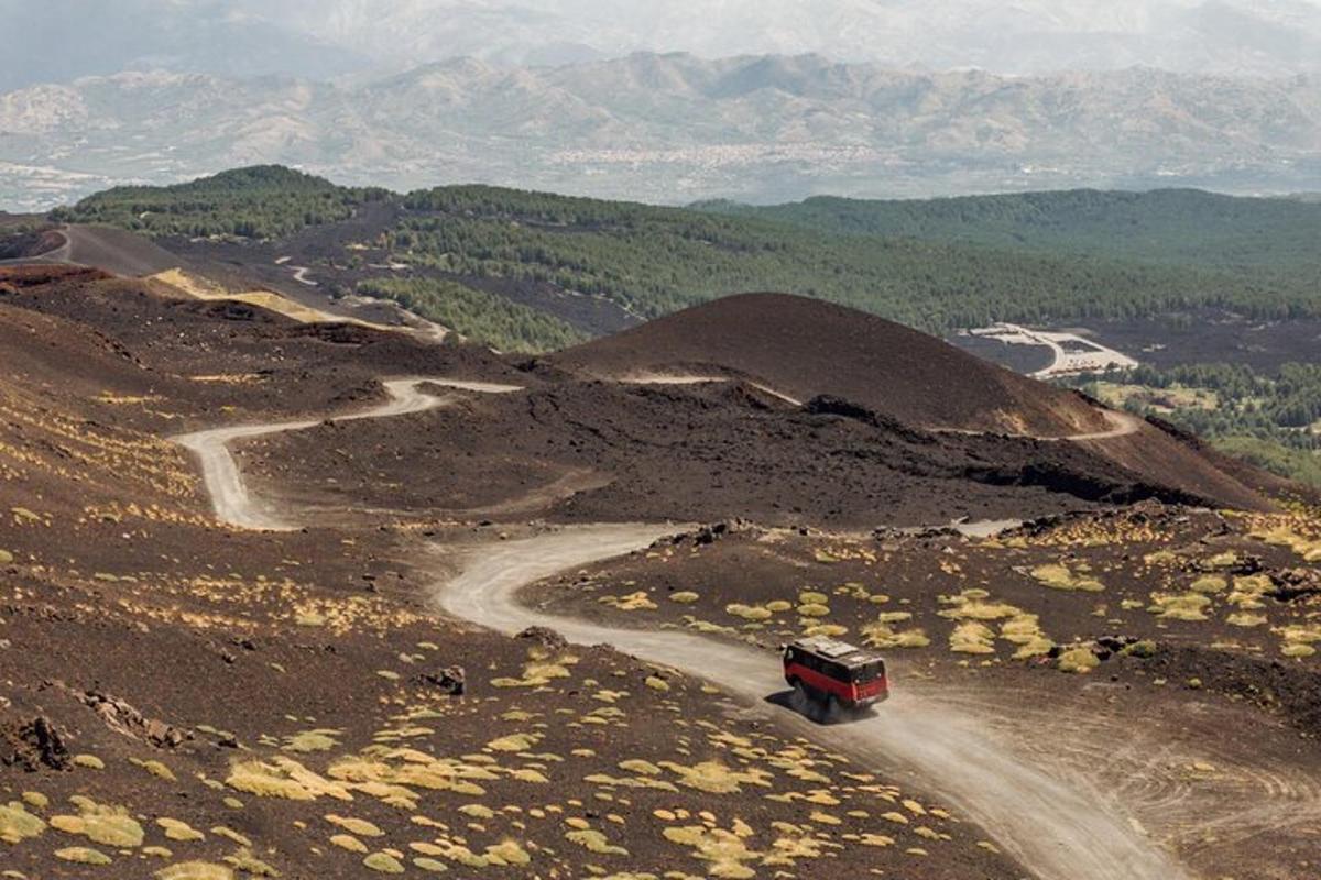 sebuah trak merah memandu di jalan tanah di atas gunung