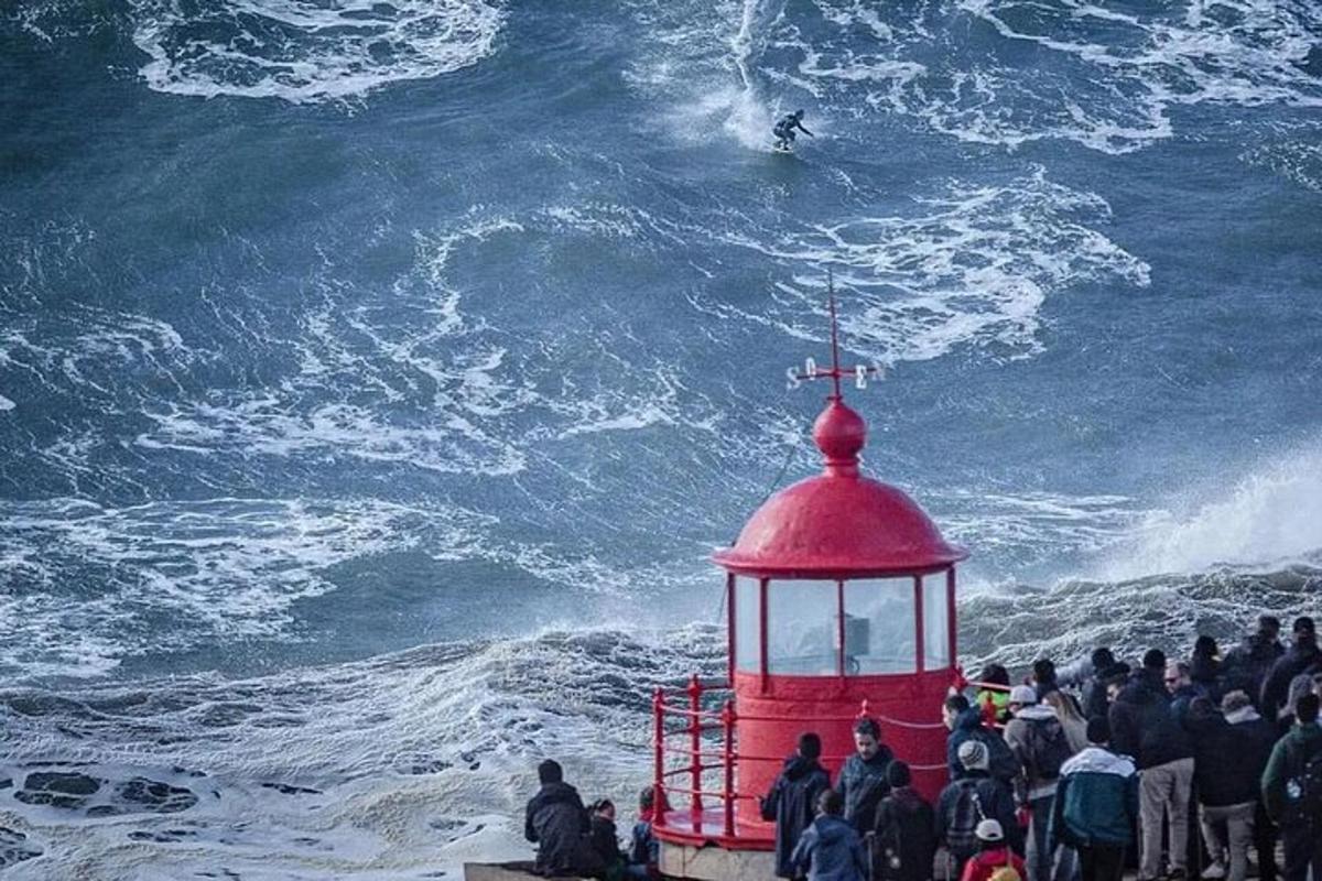 Μια ομάδα ανθρώπων που παρακολουθεί έναν άντρα που κάνει σερφ στον ωκεανό