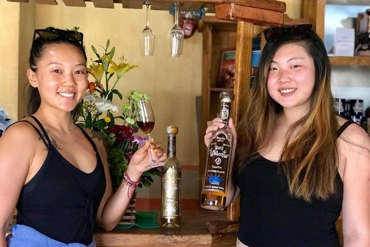 two women standing at a bar with a bottle of alcohol