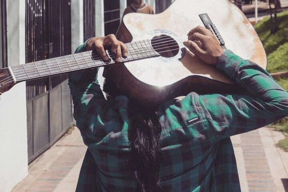seorang lelaki sedang bermain gitar di jalan