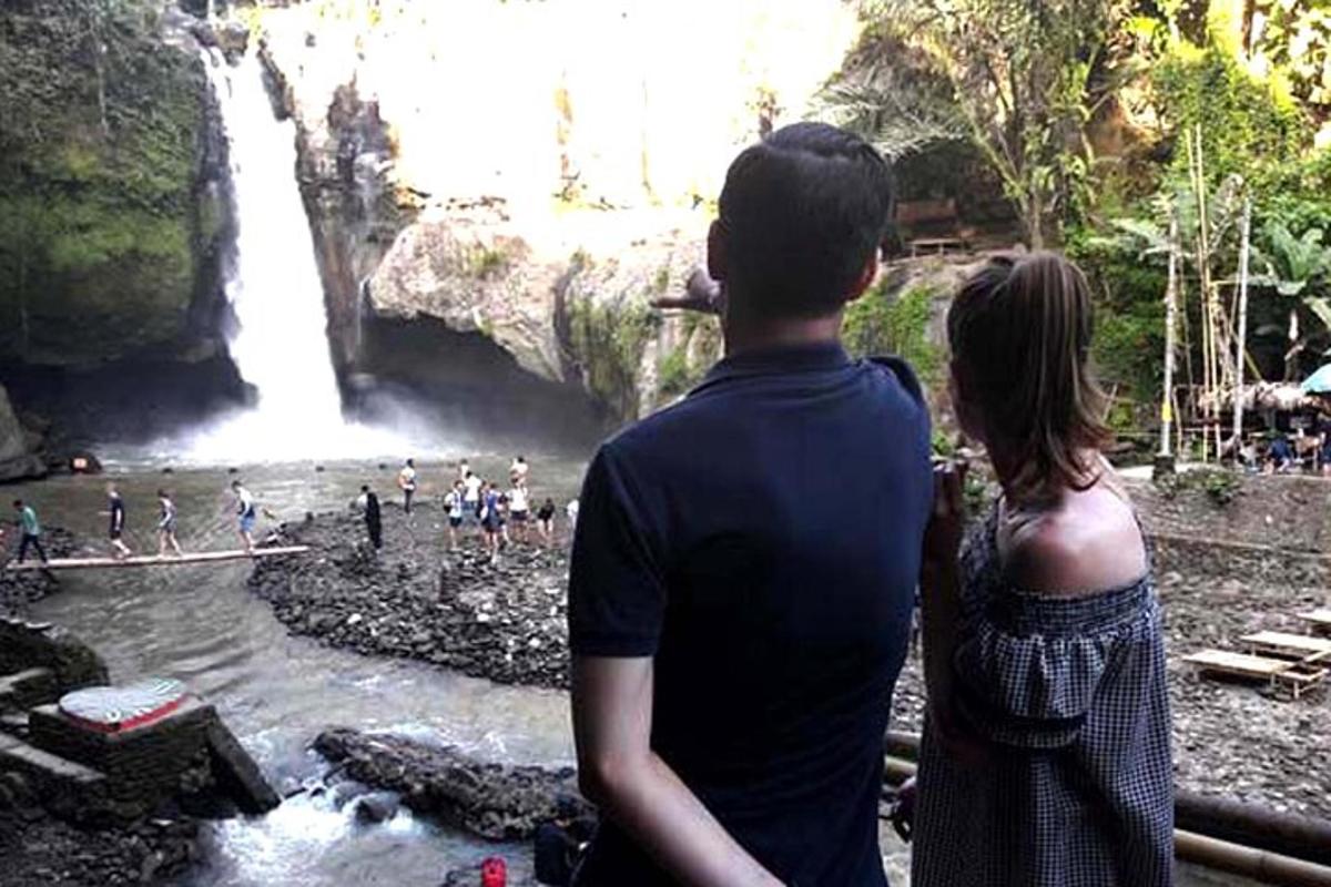 seorang lelaki dan seorang wanita berdiri di hadapan air terjun