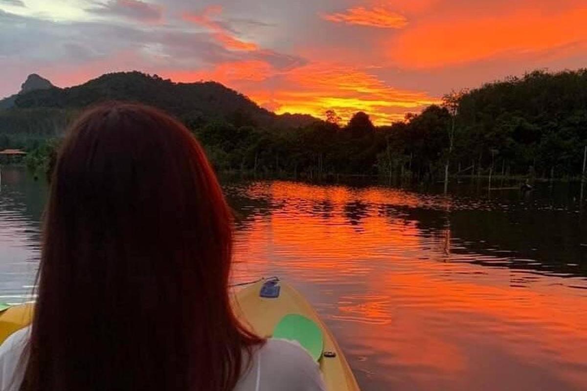 uma mulher em um barco em um lago ao pôr do sol