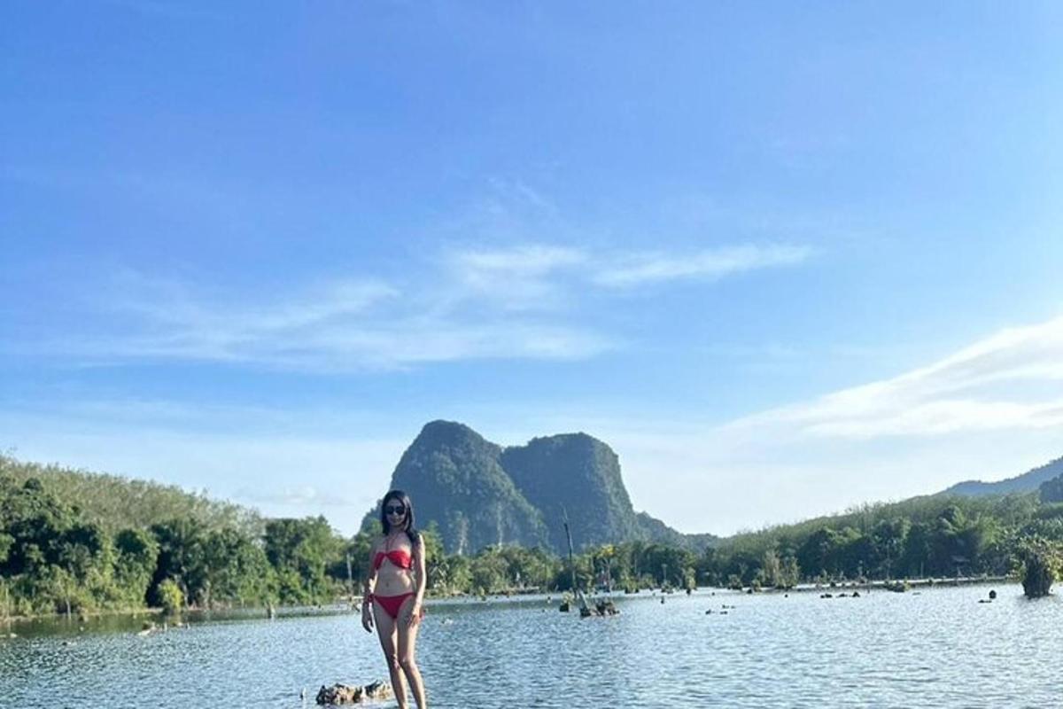 uma mulher de biquíni em pé sobre uma pedra na água