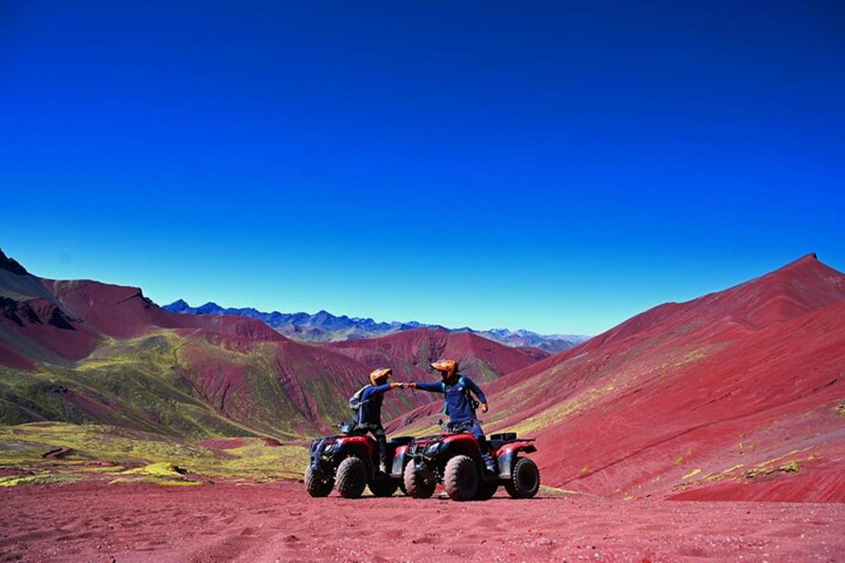 dues persones en quads per un camí de terra a la muntanya