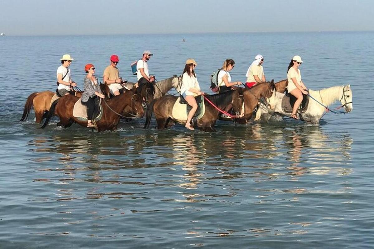a group of people riding horses in the water
