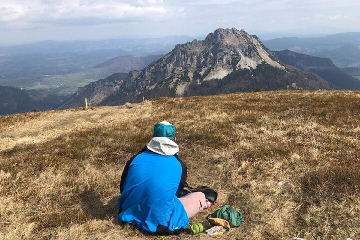 a person sitting on a hill looking at a mountain